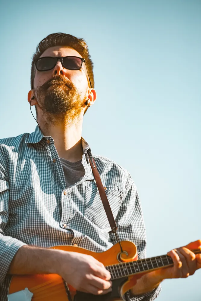 Músico tocando una guitarra eléctrica naranja al aire libre