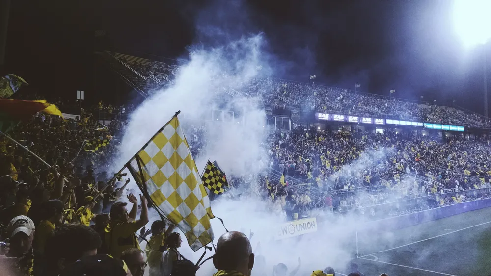 Hinchada con banderas a cuadros y humo azul